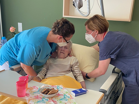 Zwei Pflegekräfte beugen sich über ein Bett und helfen einer Patientin, 3 Jahre Diakonie Hospiz Woltersdorf, Nachrichten, Diakonie-Hospiz Woltersdorf Zwei Pflegekräfte beugen sich über ein Bett und helfen einer Patientin, 3 Jahre Diakonie Hospiz Woltersdorf, Nachrichten, Diakonie-Hospiz Woltersdorf