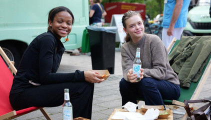 Zwei lachende Besucherinnen auf Liegestühlen blicken in die Kamera beim Albertinen-Sommerfest für die Mitarbeitenden aus den unterschiedlichen Einrichtungen der Immanuel Albertinen Diakonie am Standort Schnelsen auf dem Platz vor der Kirche am Albertinen Krankenhaus.
