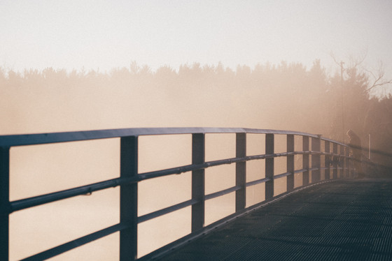 Eine hölzerne Brücke im Nebel mit einem Mann in der Ferne als Titelmotiv für die Psychodynamischen Tage Langeoog 2016.