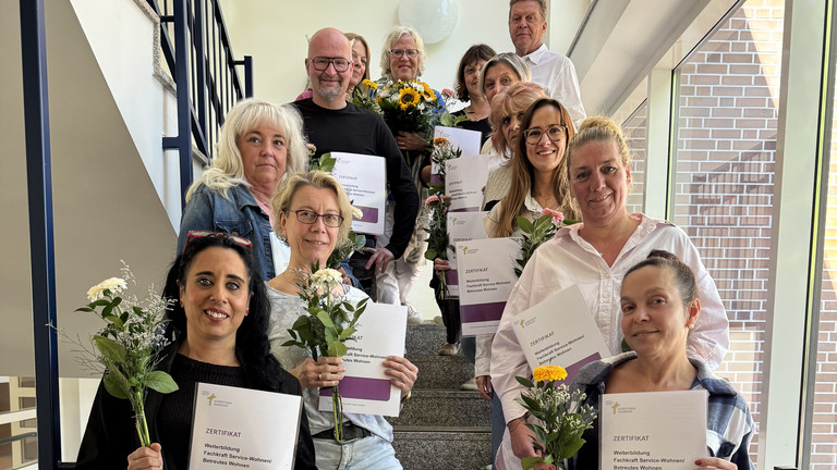 Gruppenfoto 11. Jahrgang Weiterbildung Fachkraft Service-Wohnen / Betreutes Wohnen mit Abschlusszertifikaten und Blumensträußen auf Treppenaufgang, Qualifizierung, Albertinen Akademie, Hamburg Gruppenfoto 11. Jahrgang der beruflichen Weiterbildung Fachkraft Service-Wohnen / Betreutes Wohnen mit Abschlusszertifikaten und Blumensträußen auf dem Treppenaufgang